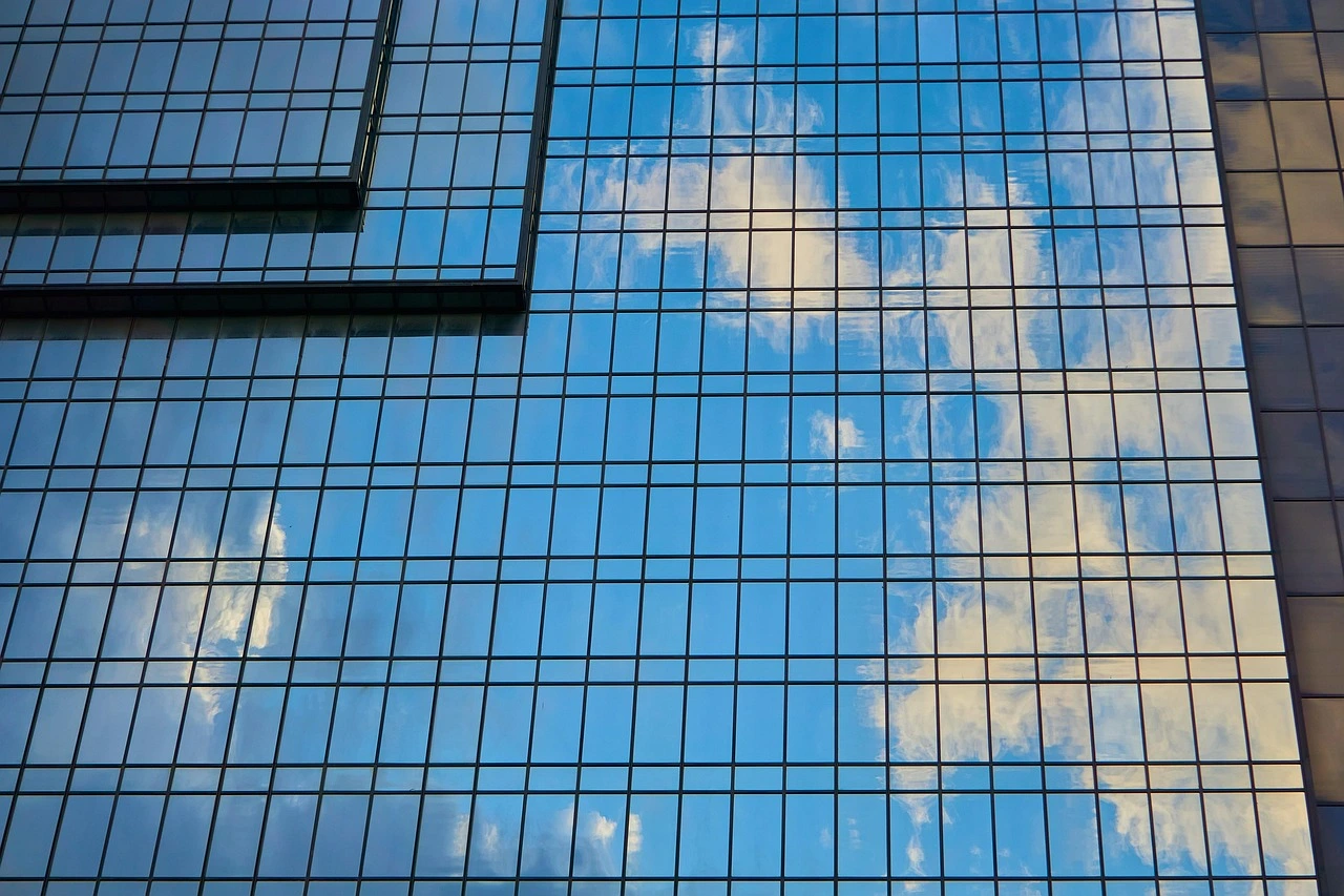 Parede de cortina de vidro refletindo o céu azul e as nuvens