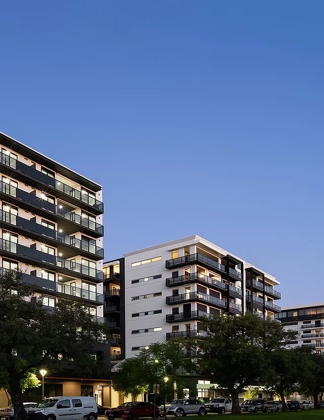 HurtleCo residential complex with lit balconies and greenery