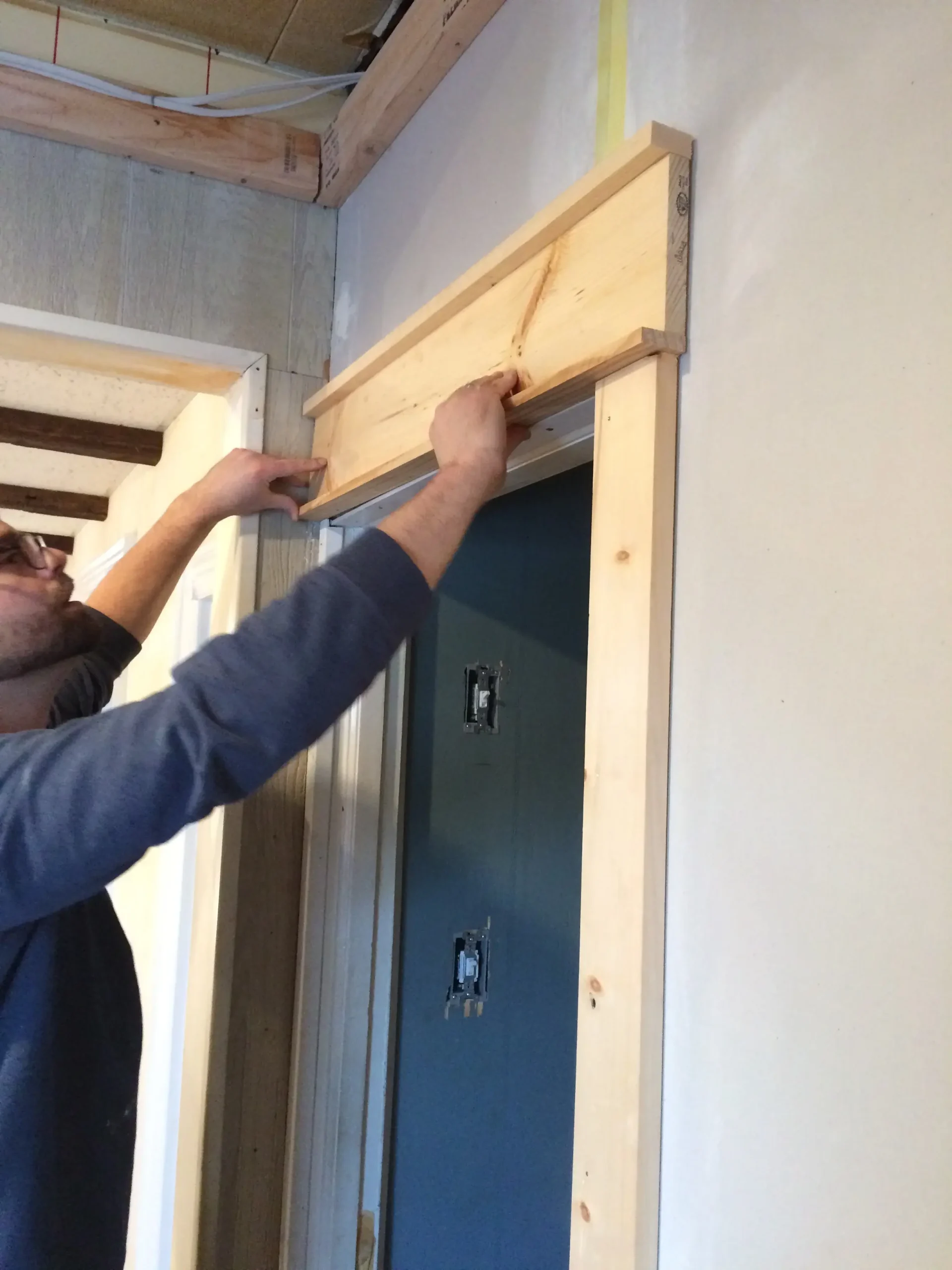 Man installing wooden trim above a door