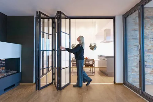 Woman opening black framed glass folding doors