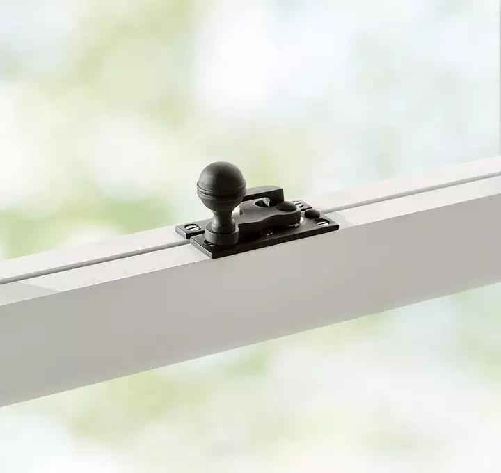 Black window lock on white window frame