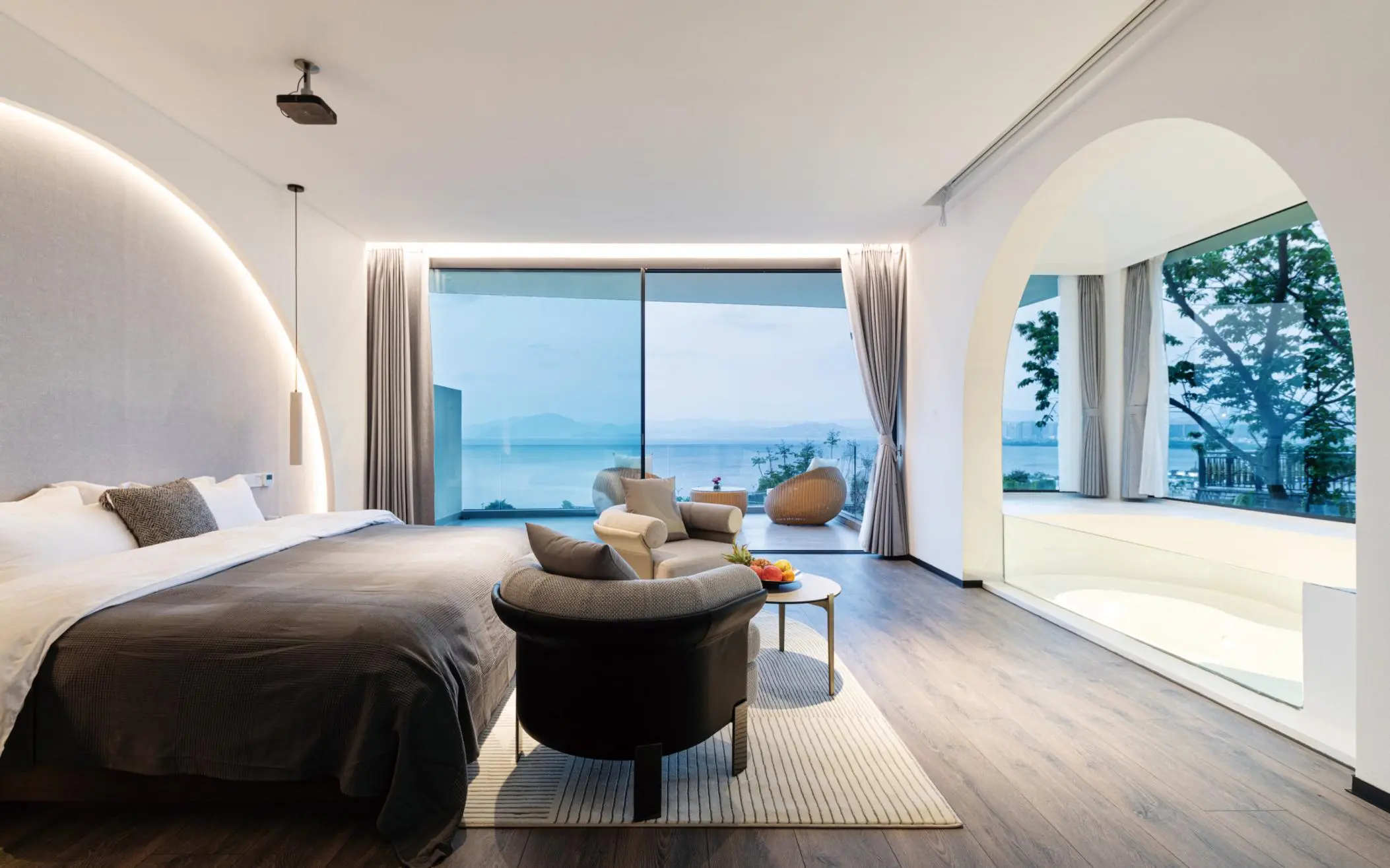 Quarto moderno com paredes curvas e janelas com vista para o mar