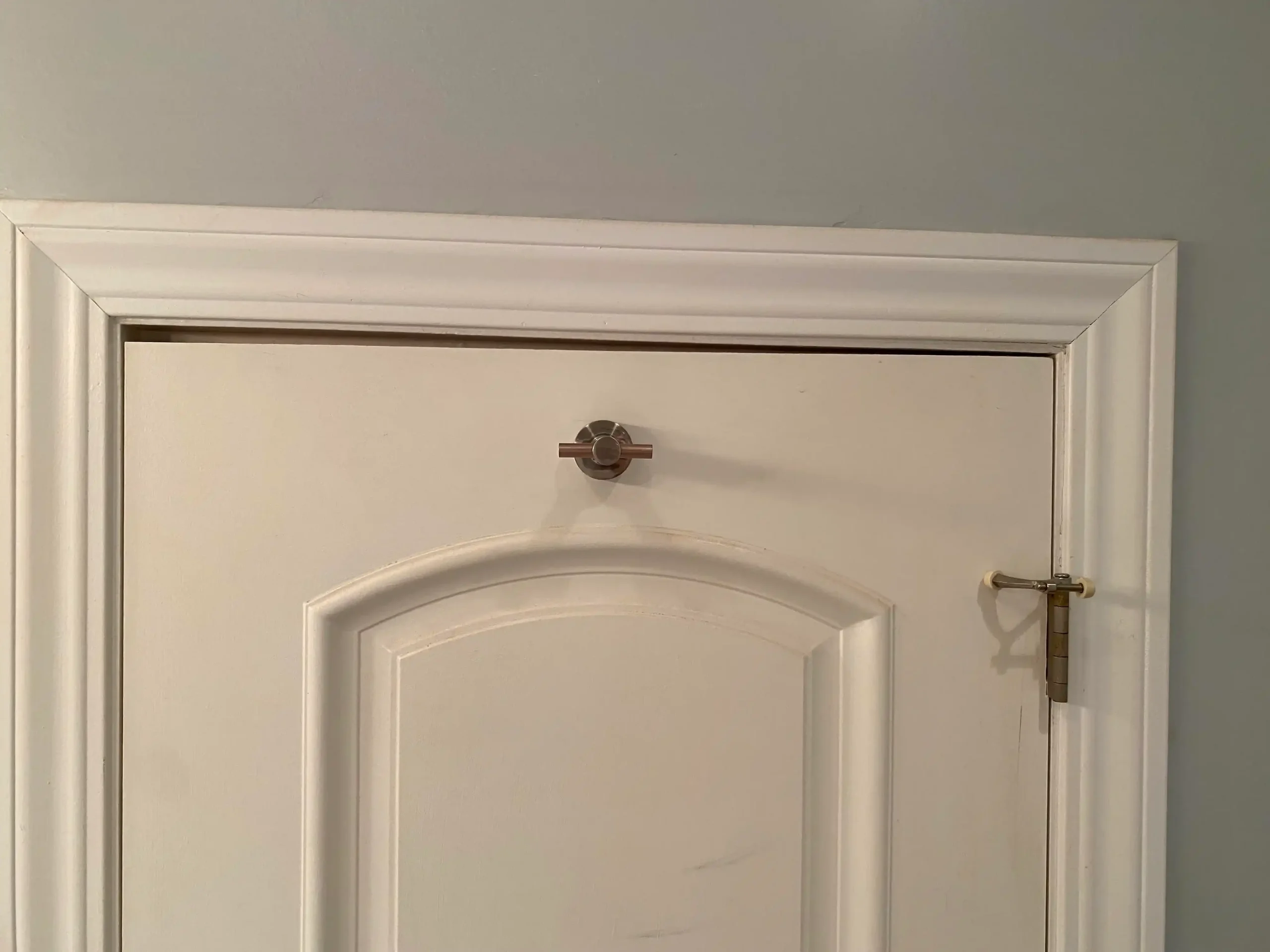 Marco de puerta blanco con moldura y pasadores de bloqueo de puerta improvisados