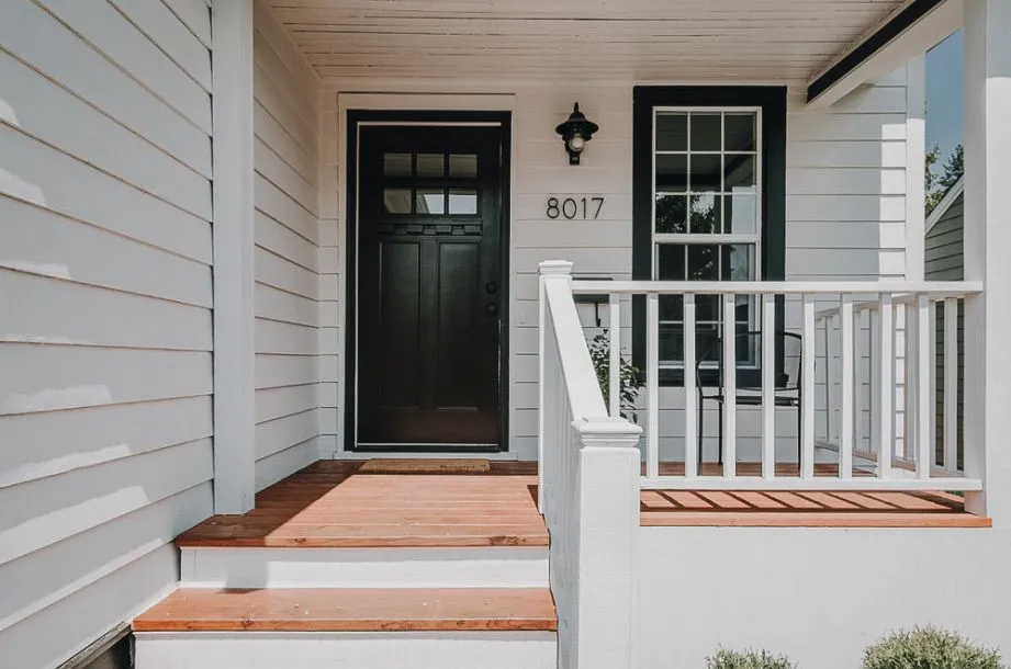 Porche avant blanc avec porte noire et numéro de maison 8017