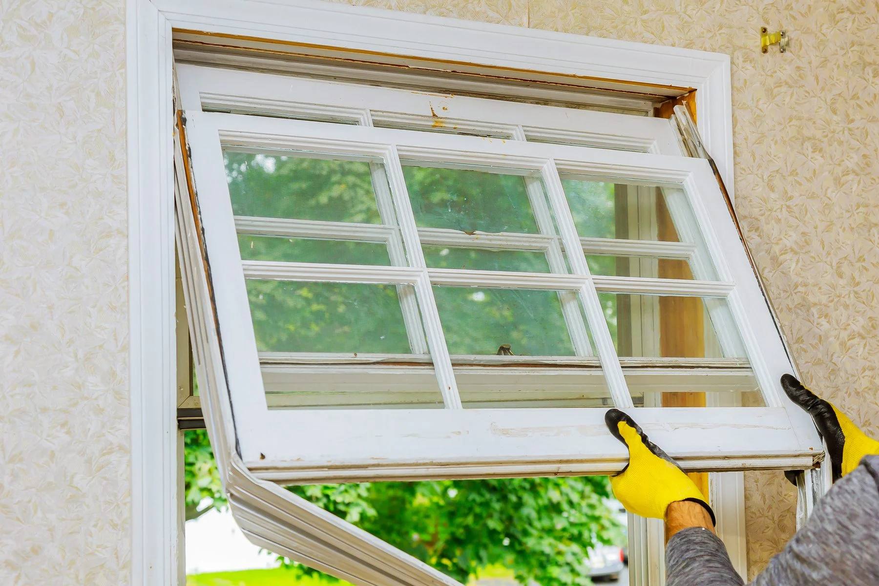 Worker removing old double hung window for maintenance
