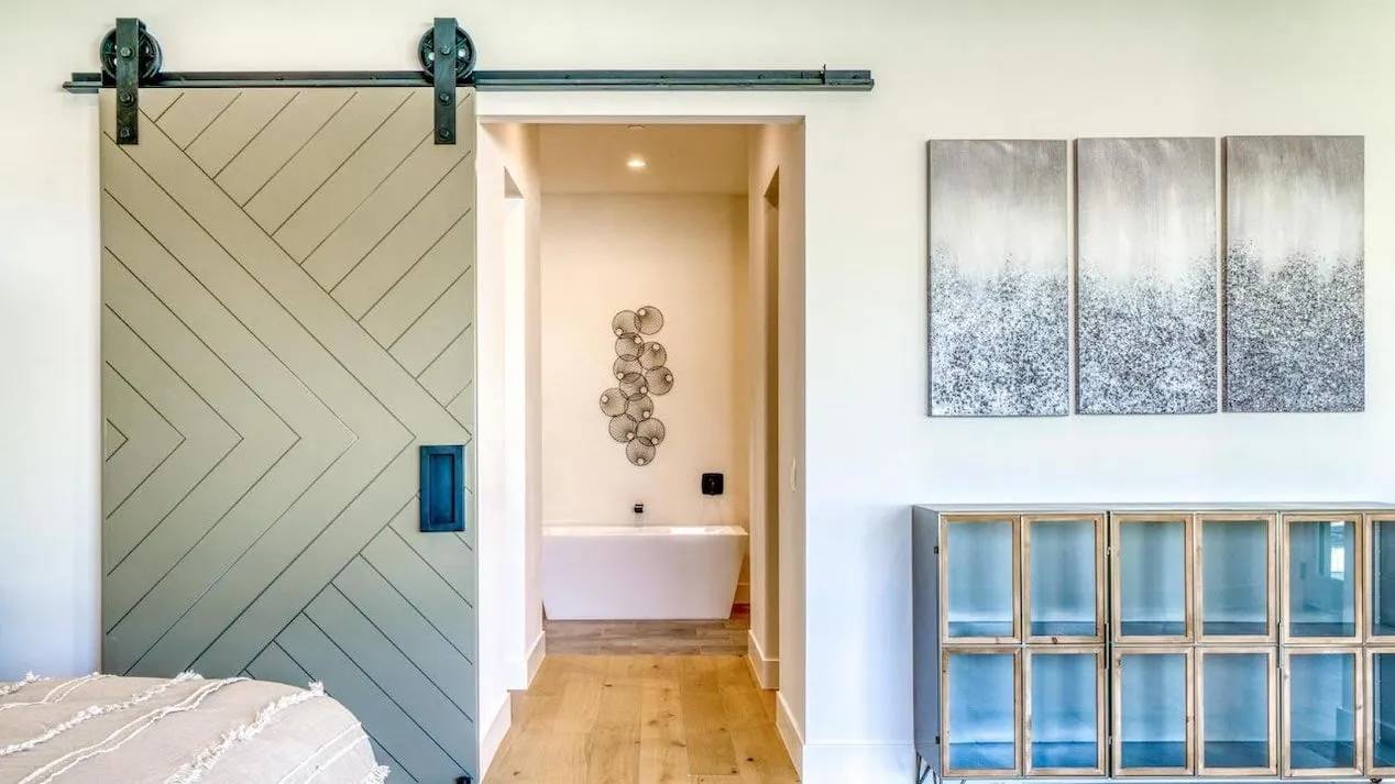 Дверь амбара с шевронным узором открывается в коридор ванной комнаты