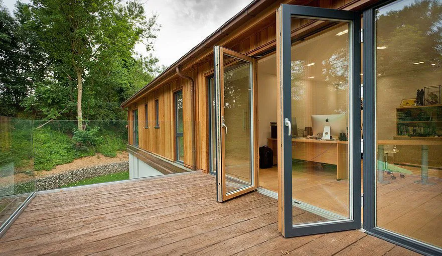 Portas de pátio compostas que se abrem para um deck arborizado e pitoresco