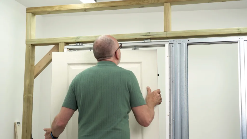 남자가 포켓 도어 프레임 구조를 설치하고 있다