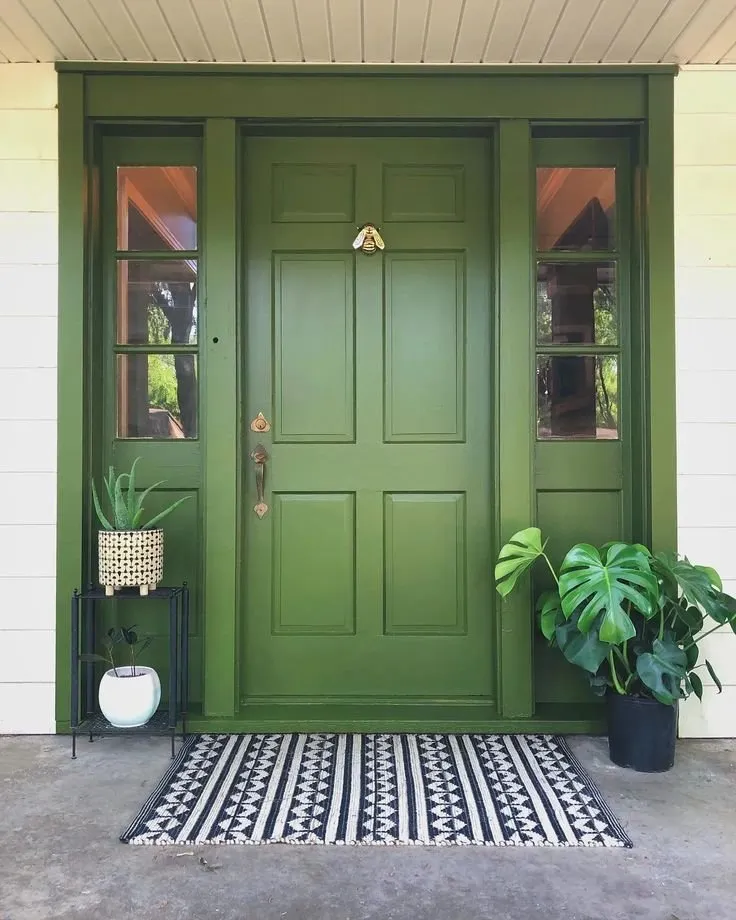 Olive green front door with side windows and plants