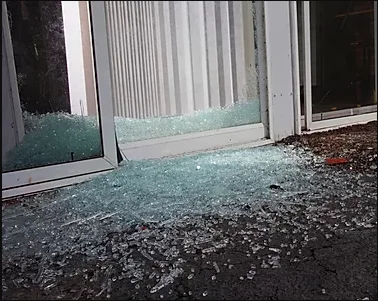 Porta de correr de vidro quebrada com vidro espalhado ao redor