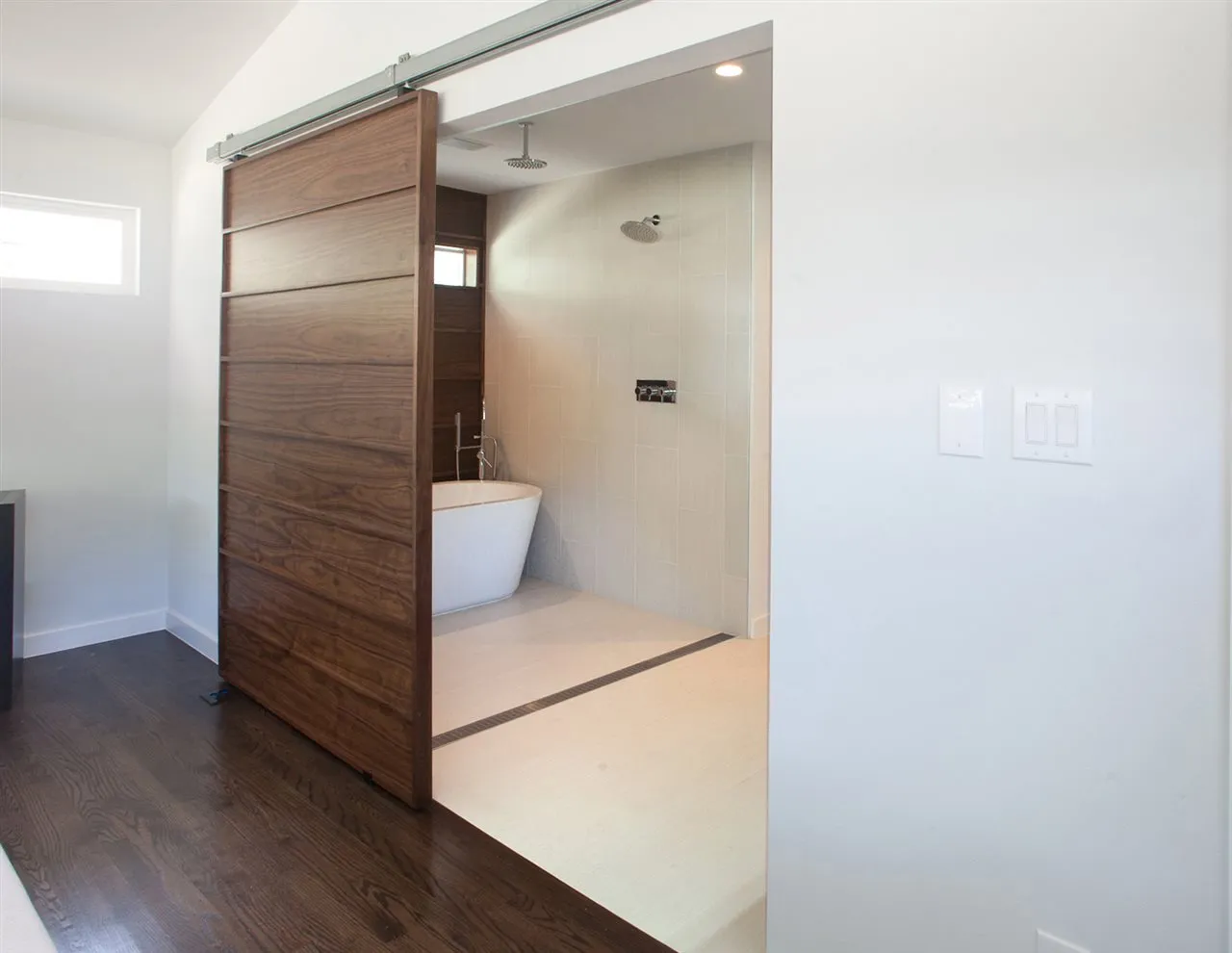 باب خشبي منزلق يفصل مساحة الحمام عن غرفة النوم