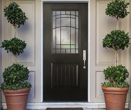 화분에 심은 나무로 둘러싸인 전통적인 검은색 강철 문