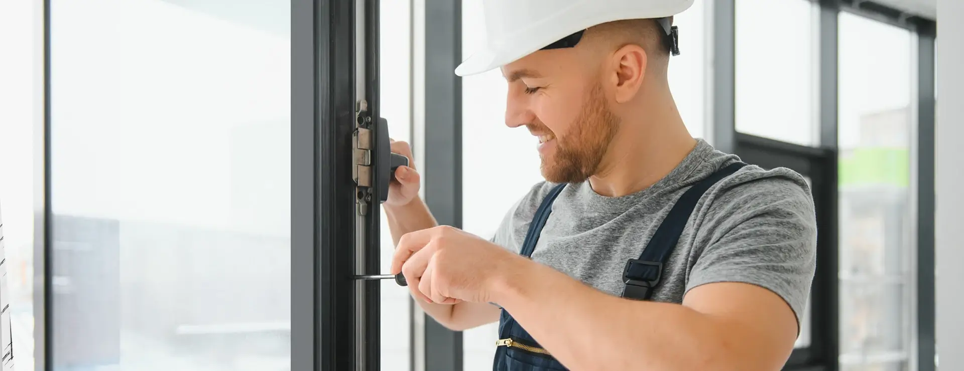 Работник, обслуживающий механизм замка алюминиевой двери