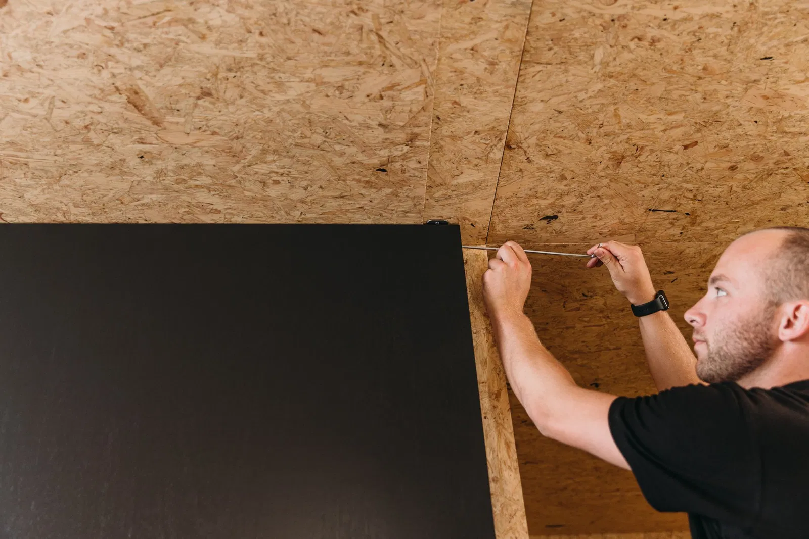 Homem instalando porta pivotante com ferramenta de teto