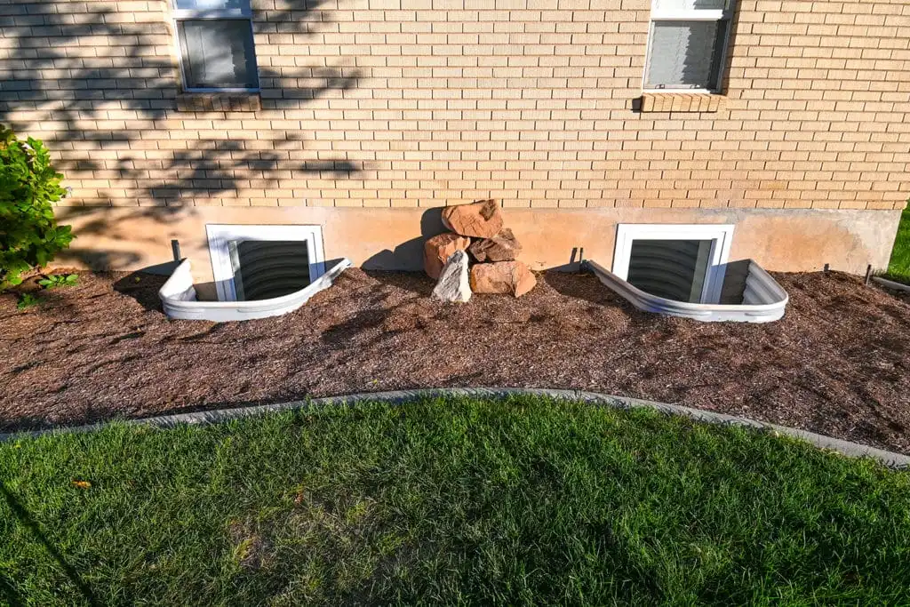 Two basement egress windows with curved metal wells