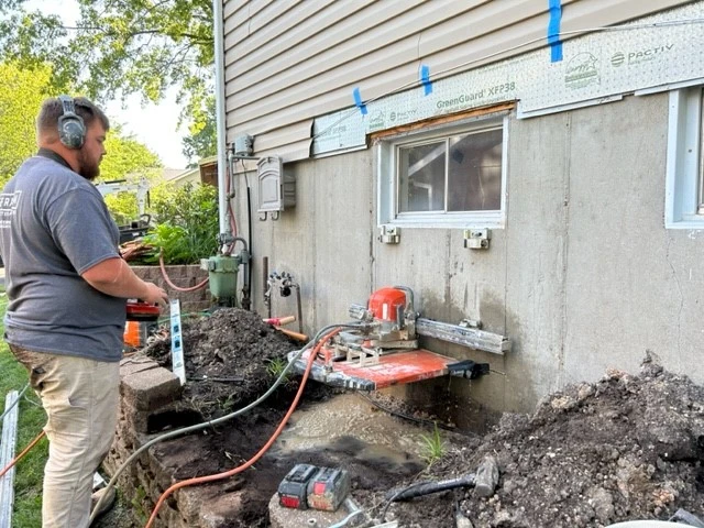 Worker cutting foundation wall for egress window install