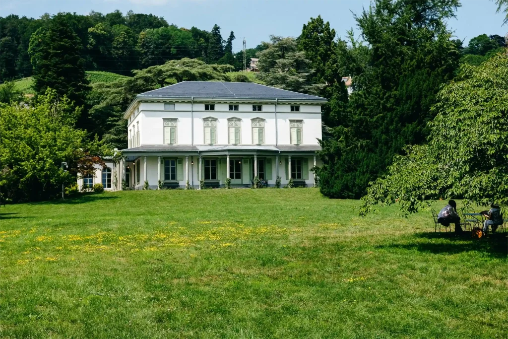 Classic villa surrounded by green field and tall trees