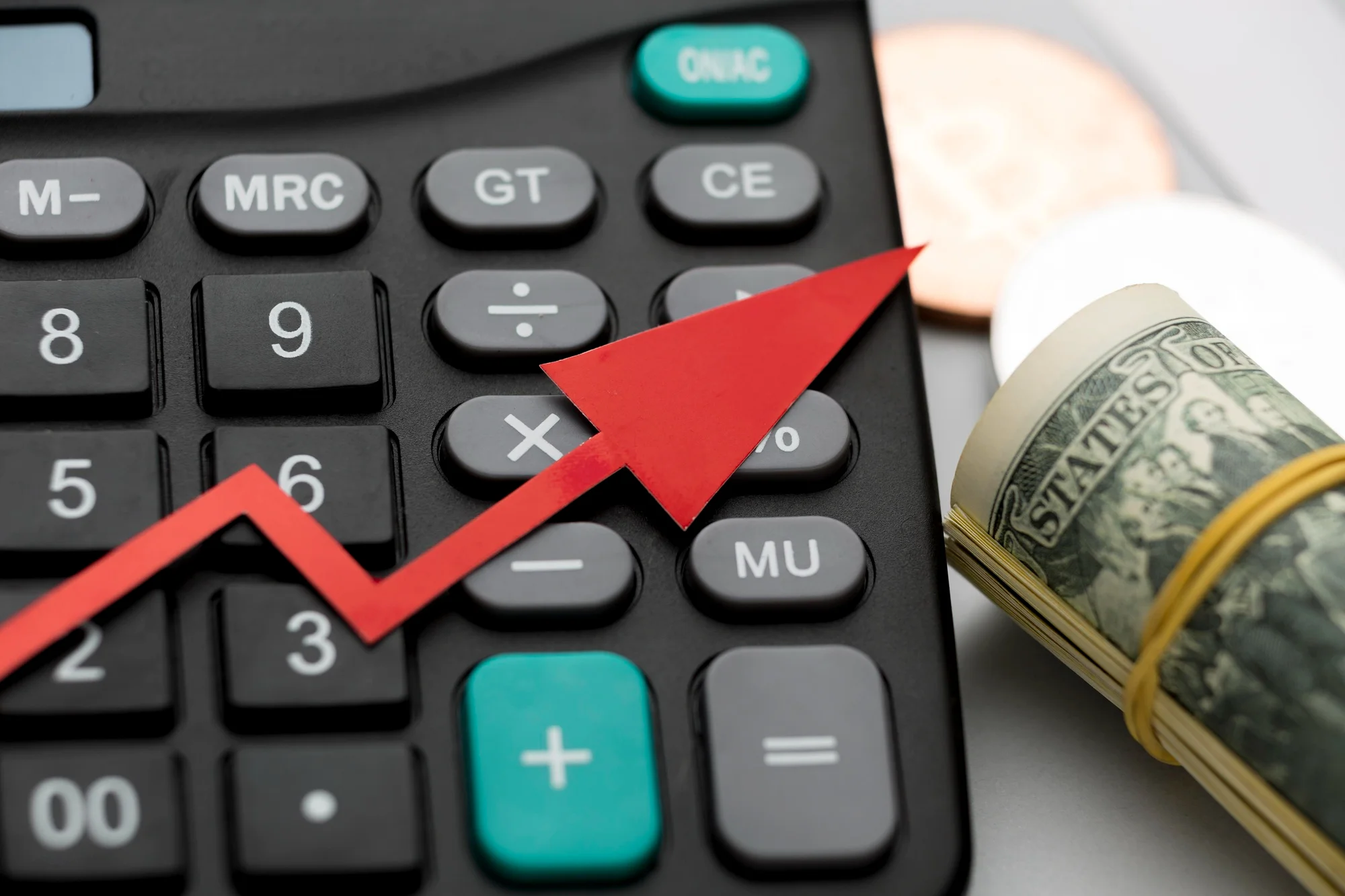 Calculadora com seta vermelha ascendente indicando aumento de custo