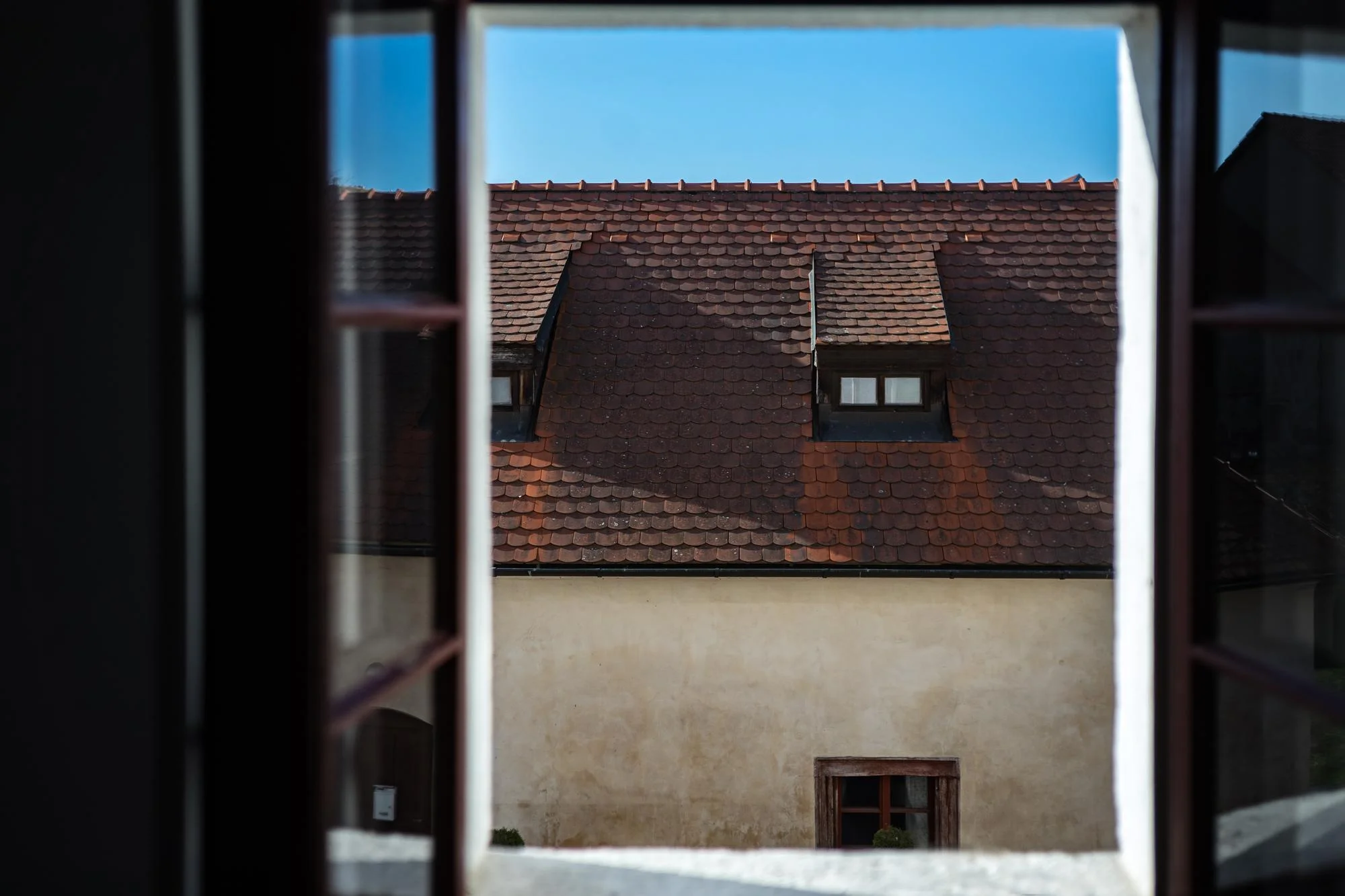 Pequenas janelas de sótão vistas através de uma janela interior aberta.