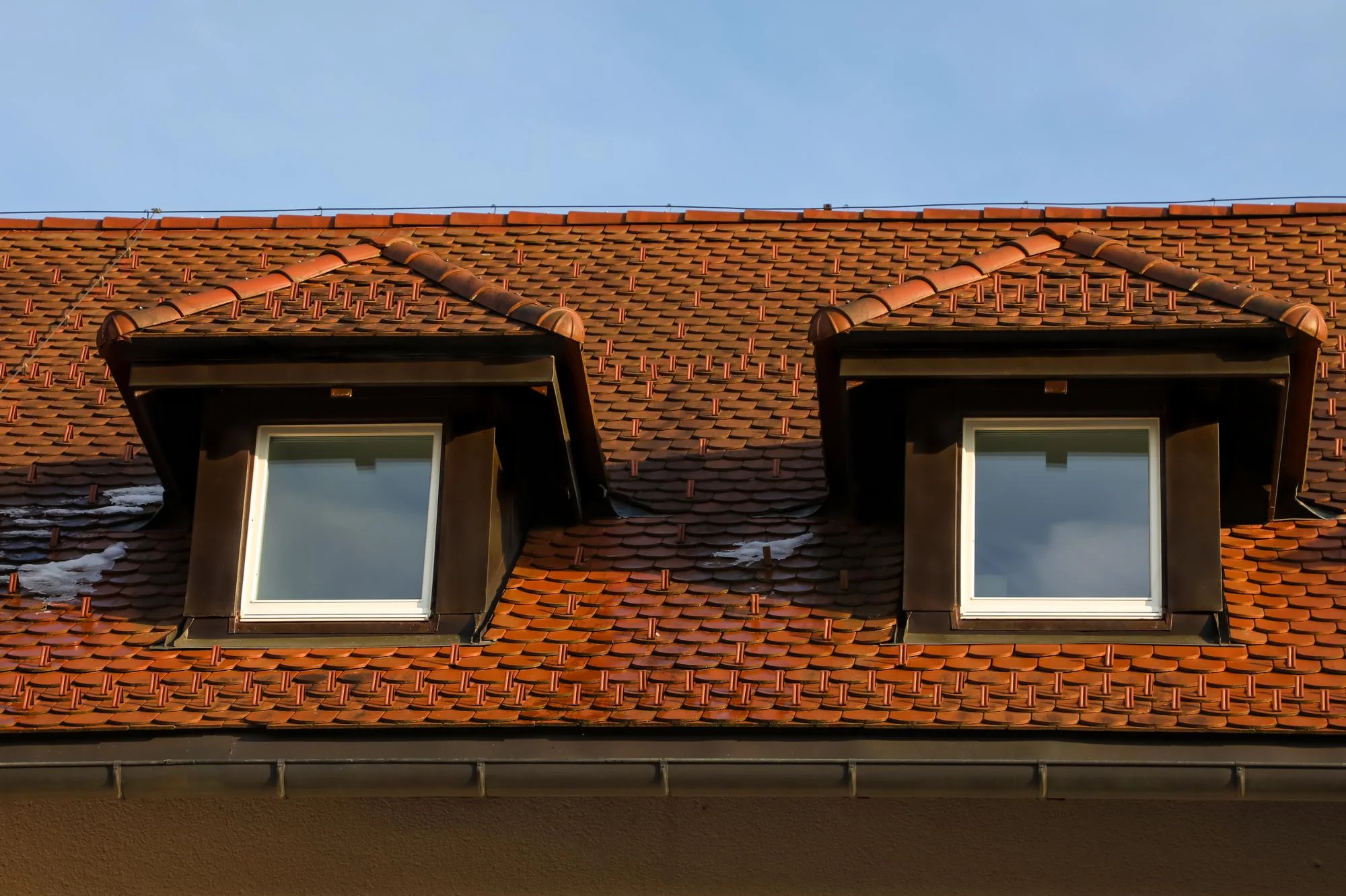 Duas janelas de sótão com empena dupla em telhado de telha vermelha