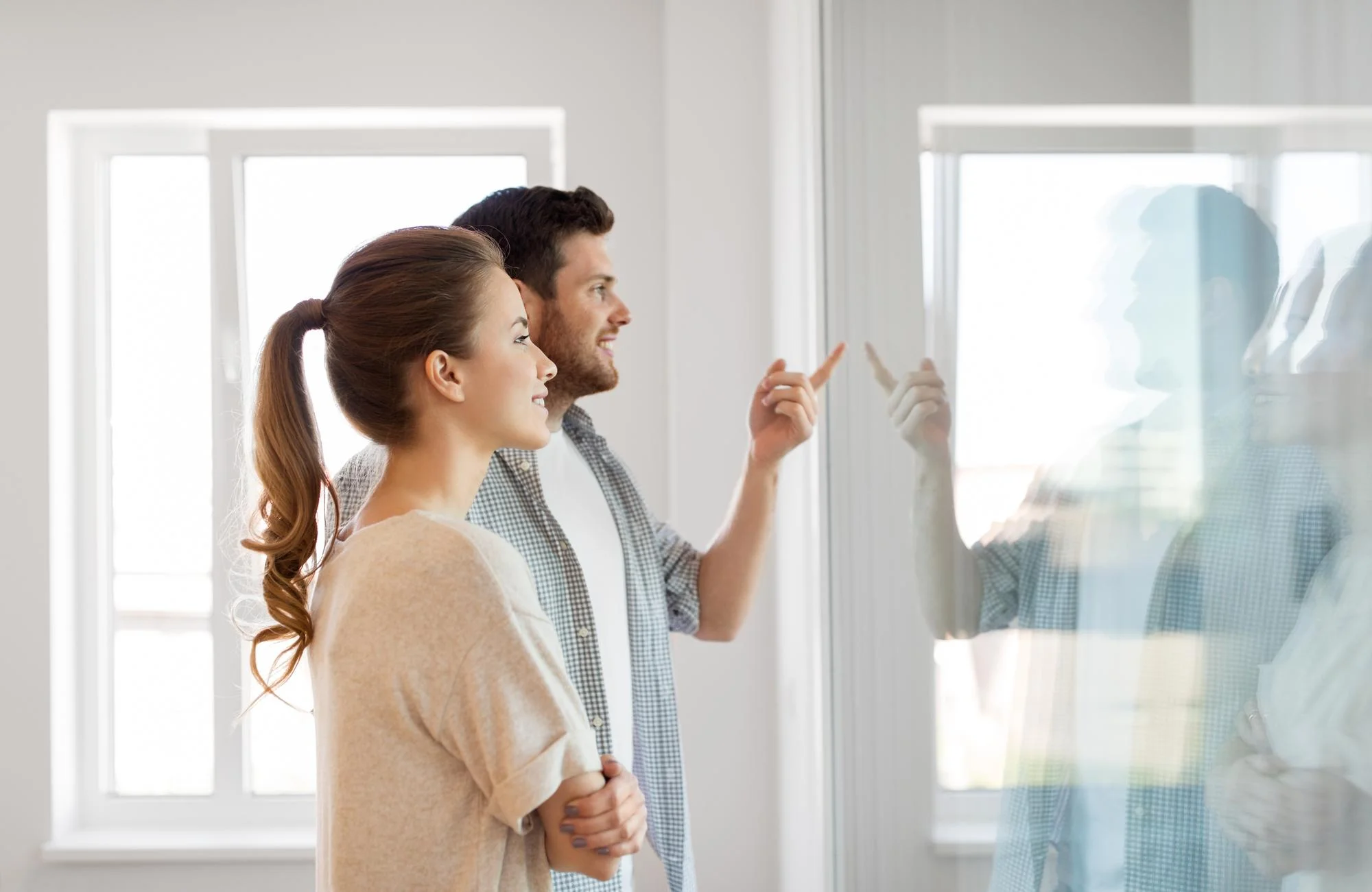 Couple reviewing window placement in bright living space