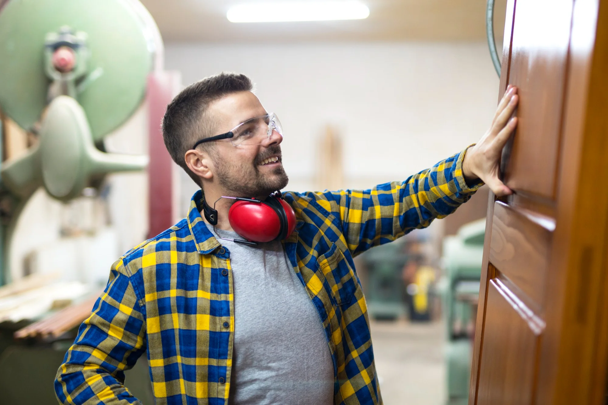 Craftsman inspecting solid wood door in workshop
