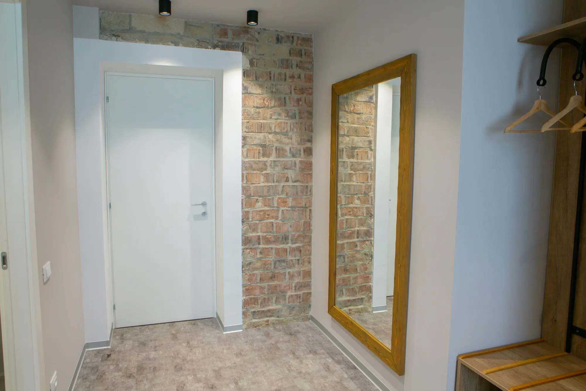 Large hallway mirror beside white door and brick wall