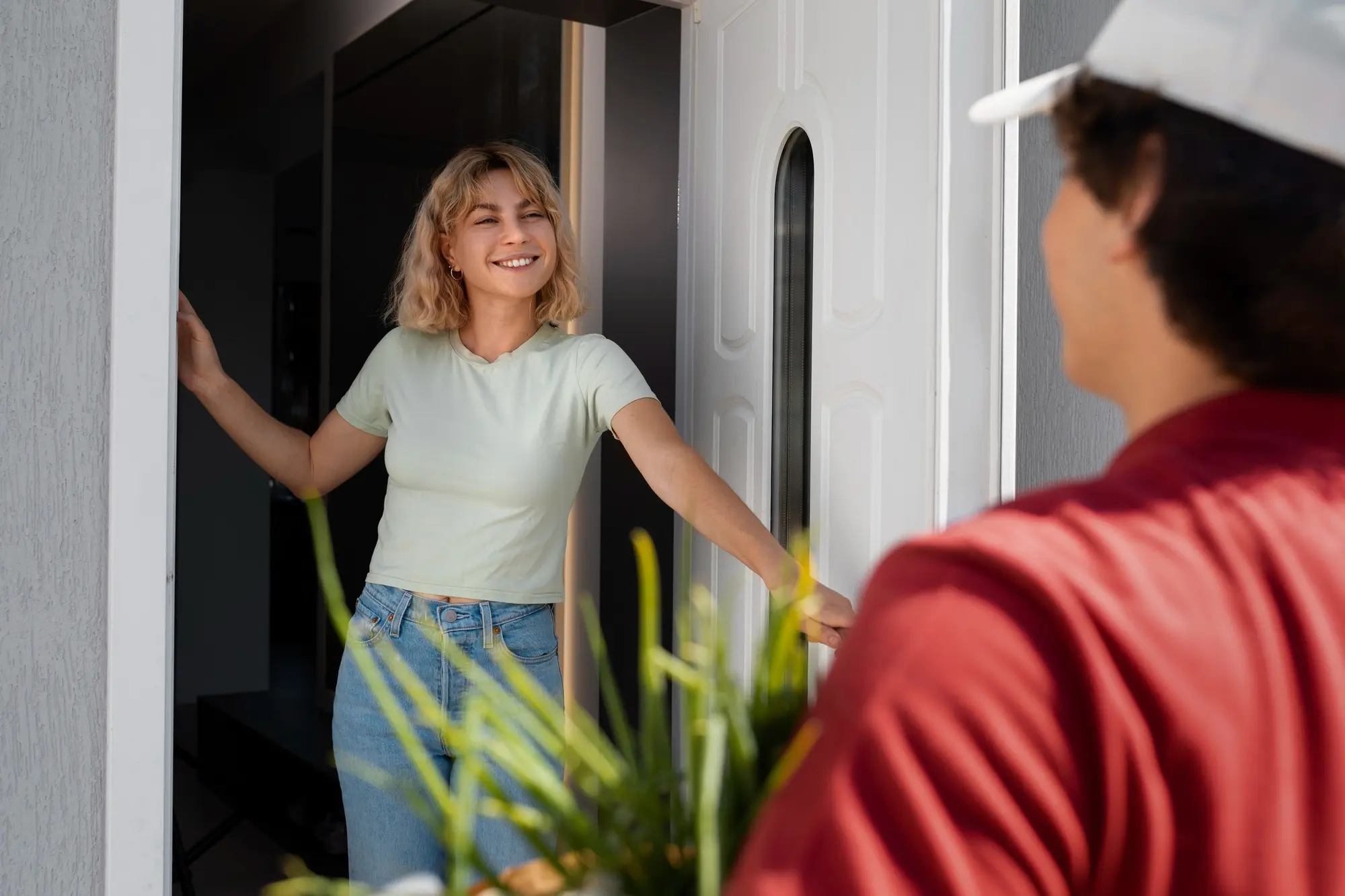 Smiling woman greeting visitor at her front door