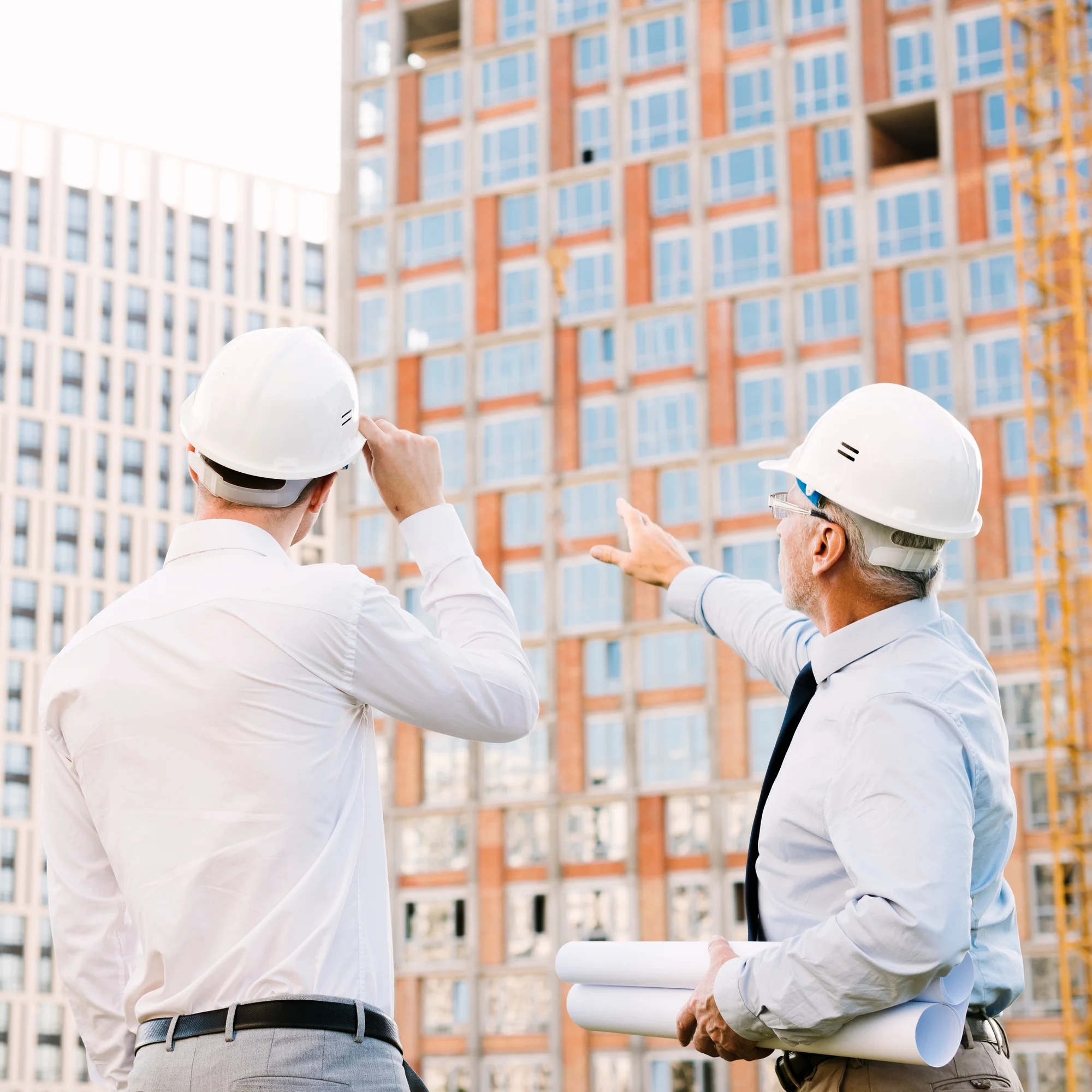 Des ingénieurs inspectent le chantier avec des plans et des casques.