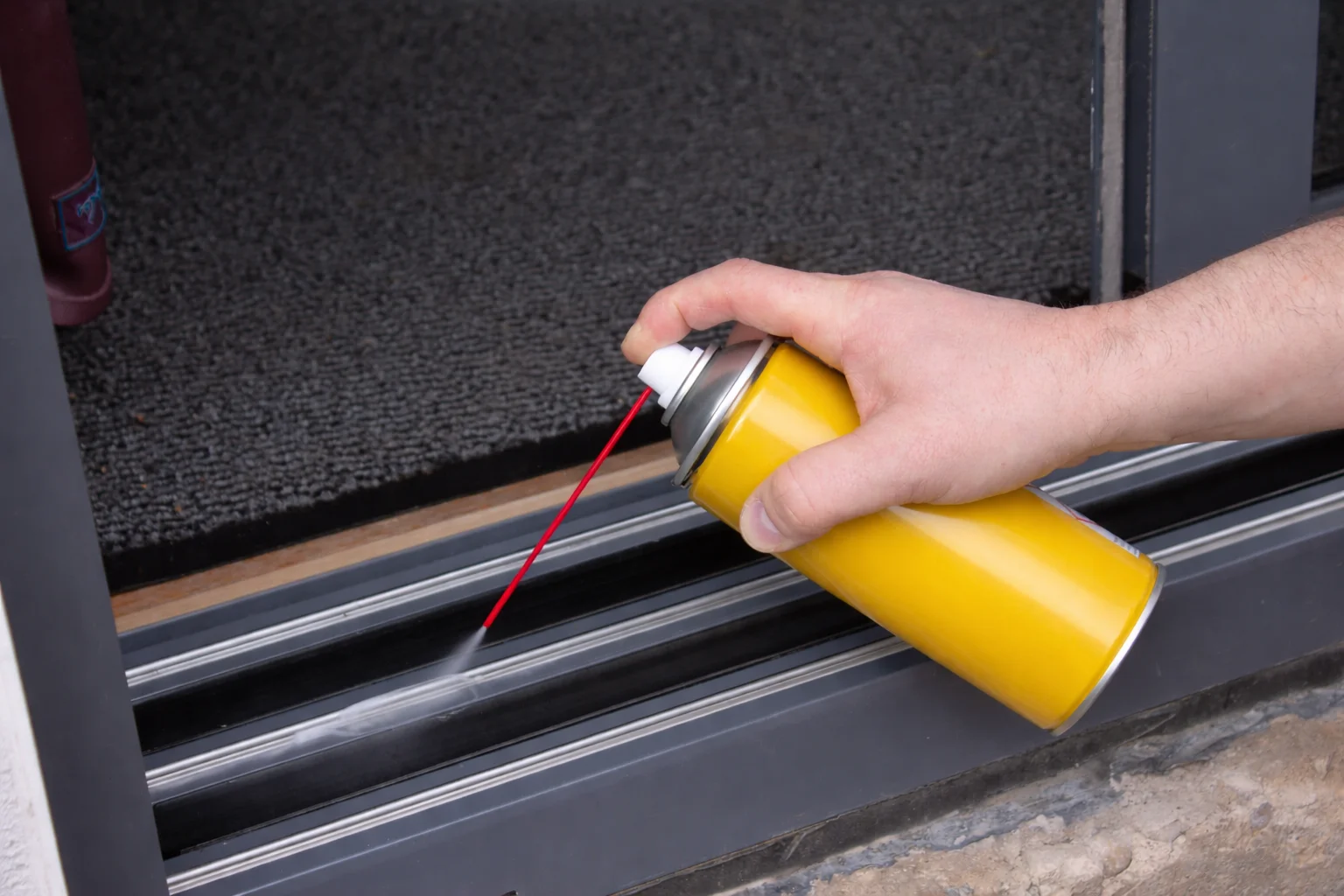 Pulvérisation de lubrifiant PTFE sur le rail de la porte coulissante en verre