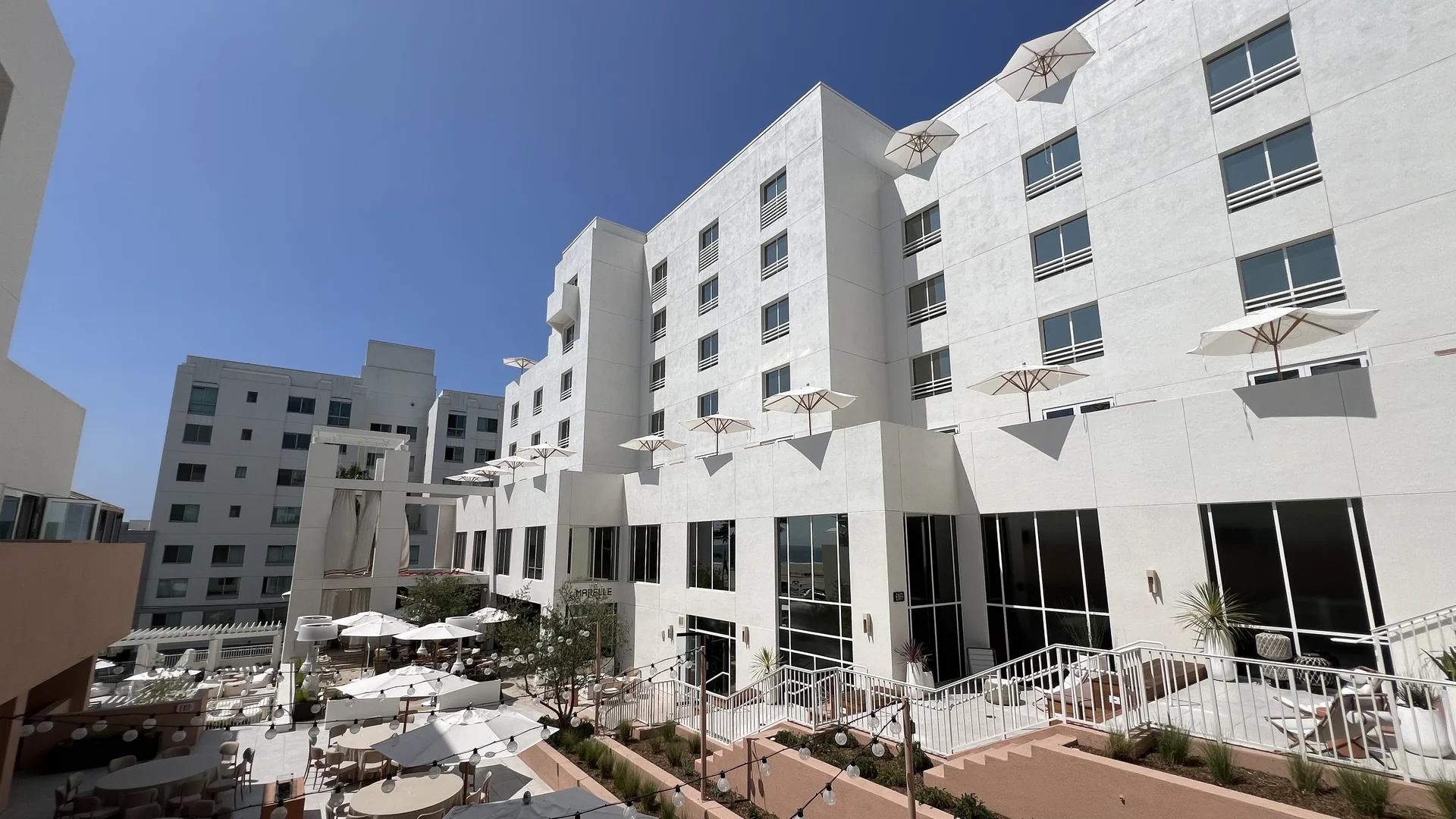 Central courtyard and hospitality terrace of Sandbourne Santa Monica highlighting multi-story guestroom facade fenestration